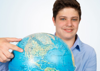 Aaron zeigt auf einem Globus auf die USA | © Mrn GmbH