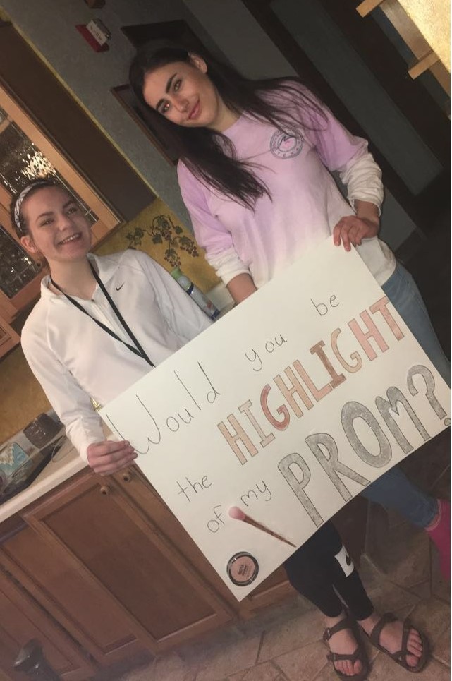 Hanna und ein Mädchen halten ein Poster mit einer Einladung zum Prom in den Händen  | © Hanna Vogel